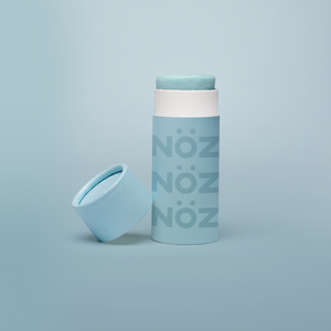 Blue Noz stick sunscreen with the cap off modeled in a Blue background