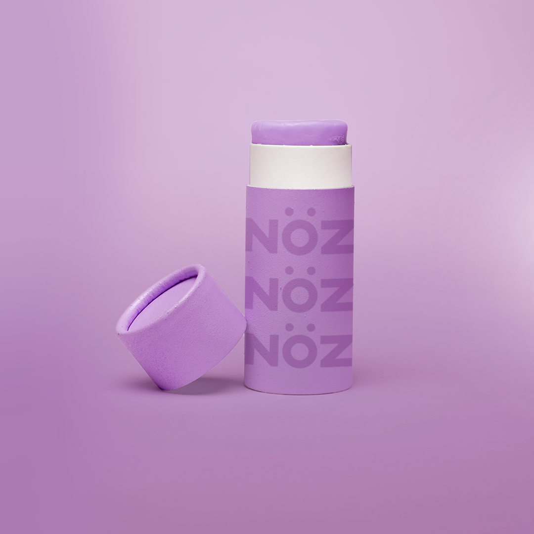 Purple Noz stick sunscreen with the cap off modeled in a purple background