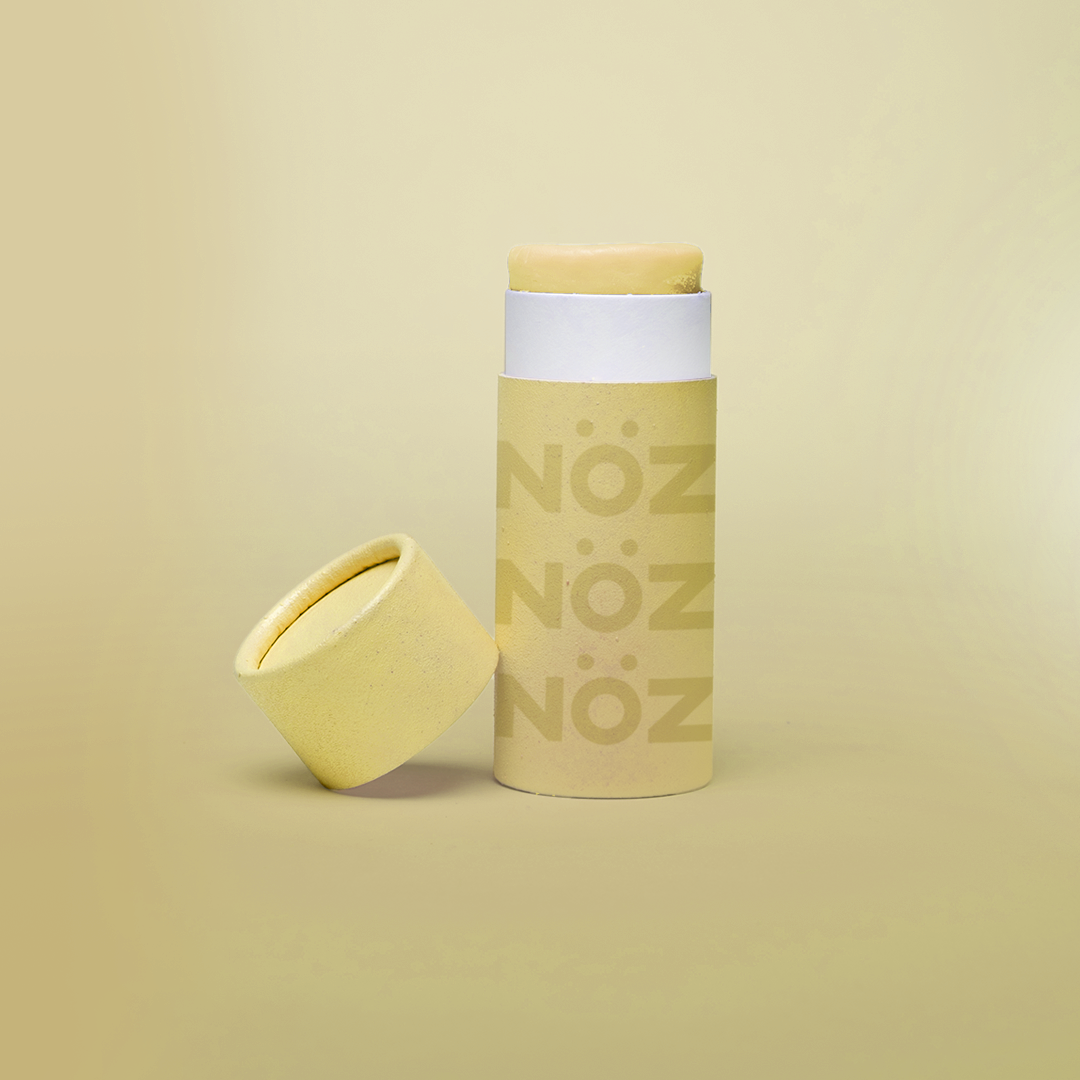 Yellow Noz stick sunscreen with the cap off modeled in a yellow background